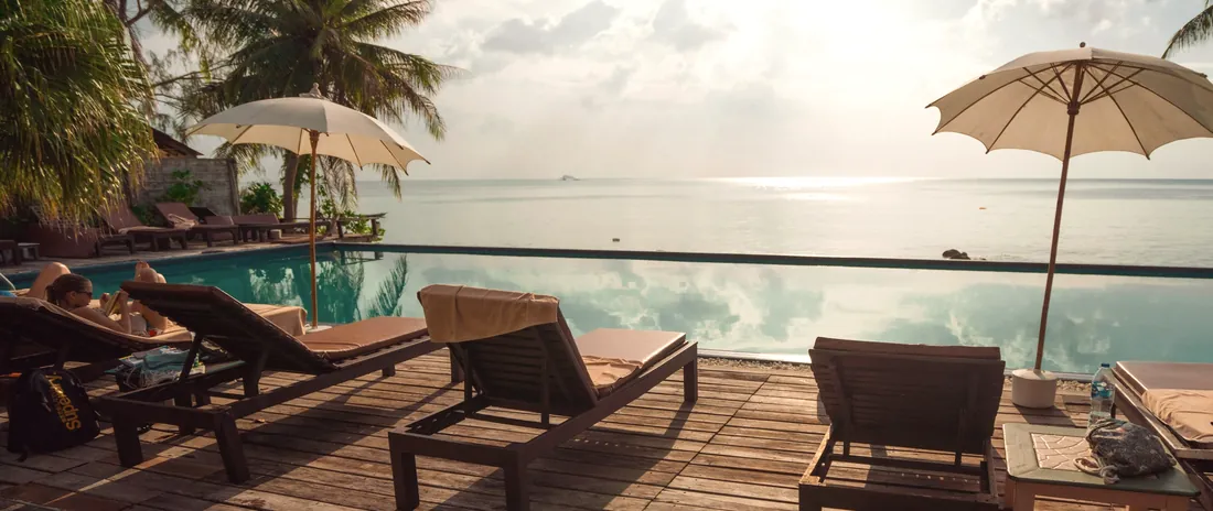 A wooden deck with loungers overlooking the sea at sunset