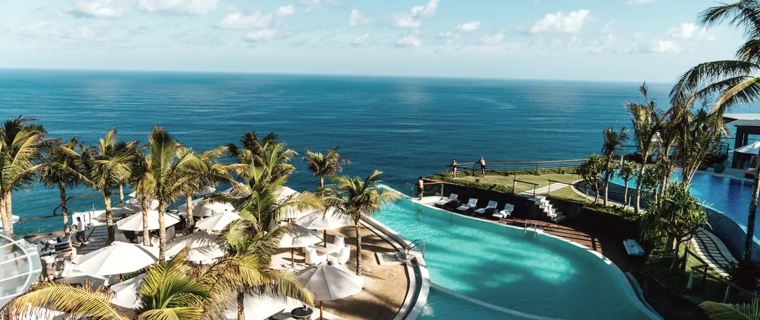 Aerial view of a coastal resort with pools and umbrellas