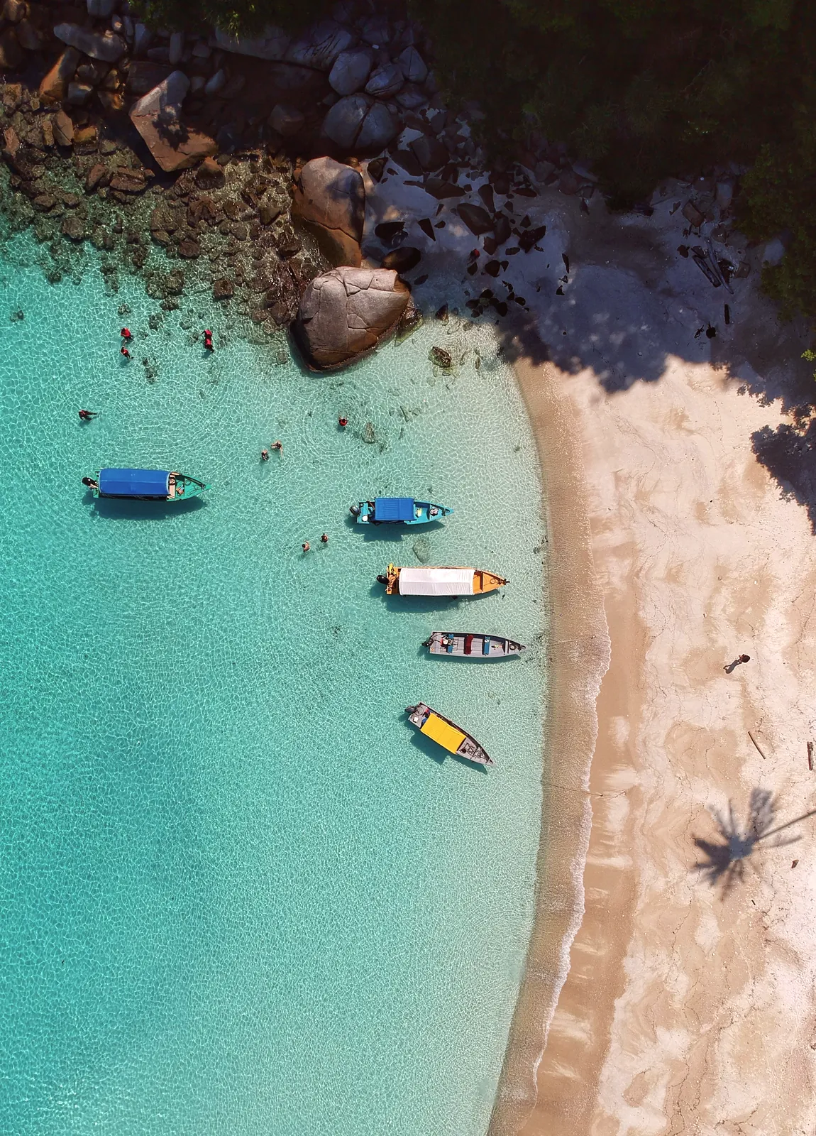 Aerial view of a sandy bay with turquoise water and small boats